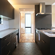 ペニンシュラ型のキッチンの床は磁器質タイルで、木目との相性も抜群！ 家事動線も考慮して、脇にはパントリーも完備されています。